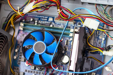 Old blue cooler fan with motherboard and colorful cables inside a computer.