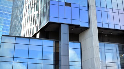 Obraz premium Blue curtain wall made of toned glass and steel constructions under blue sky. A fragment of a building.