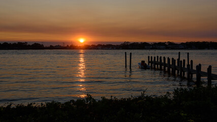 Naklejka premium A dock and pilings early morning with an orange sunrise