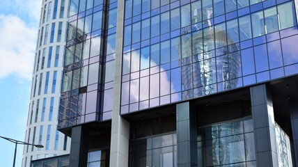 Blue curtain wall made of toned glass and steel constructions under blue sky. A fragment of a building.