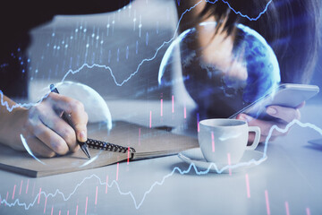 Double exposure of forex graph sketch hologram and woman holding and using a mobile device. Stock...