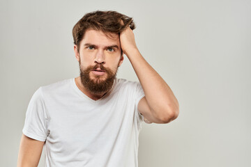 bearded man gesturing with his hands in a white t-shirt aggression light background