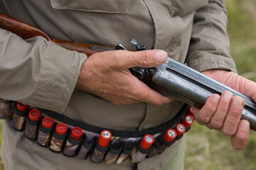 Close up of hunter loading shotgun, holds a gun and ammunition in his hand.