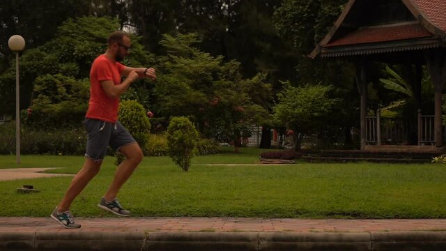 Man checking time on watch during jogging in city park, slow motion