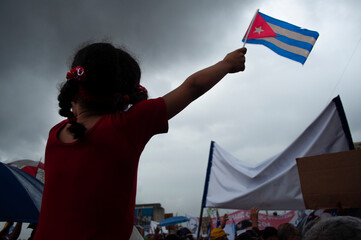 Little girl on the shoulders of her dad raising a Cuban flag in a march