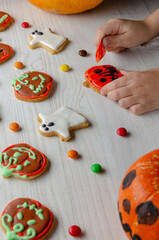 child decorates cookies for halloween. Top view