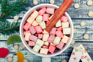 Cup of tasty hot chocolate drink with marshmallow and cinnamon stick on wooden background, Christmas decorations. A drink for the winter. Top view. Close up.