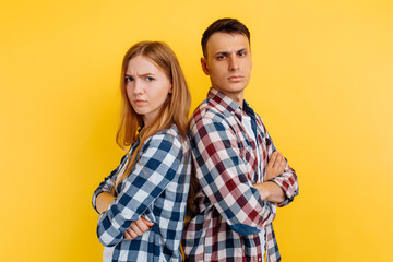 Offended young couple, man and woman standing back to each other, couple in quarrel on white background