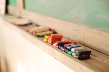 rectangle beeswax crayons lined up along shelf below chalkboard