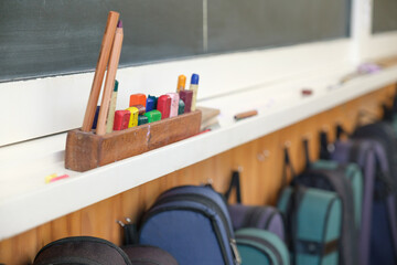 Blackboard with crayons and pencil and line of violin cases hung below