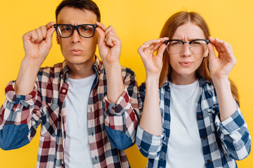 Happy young people, man and woman wearing glasses for vision on yellow background