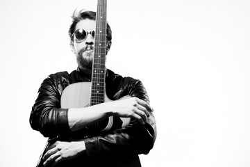 Fototapeta na wymiar A man holds a guitar in his hands music emotions black leather jacket dark glasses studio light background