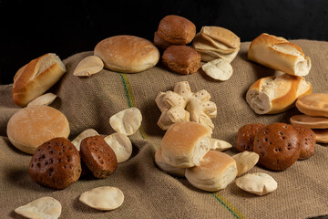 
production of different bakery breads, common bread, black bread, breadsticks, fat bread, on rustic burlap cloth