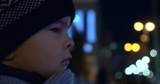 Child Stands on Street Watching Police Flashing Lights Busy City Traffic at Night Downtown Street. Blurred Background
