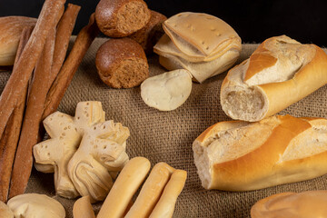 
production of different bakery breads, common bread, black bread, breadsticks, fat bread, on rustic burlap cloth