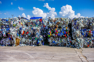 Mixed bales of post-consumer film and bags stacked three high in material recovery facility outdoor...