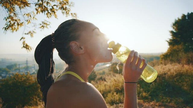 Caucasian slim sportswoman at sunrise drinking water having active physical training outdoor. Active people. Fitness girl. Inspiration and self-motivation. Healthy lifestyle.