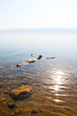 Fototapeta na wymiar Woman floating in the Dead Sea, Jordan. One person, copy space.