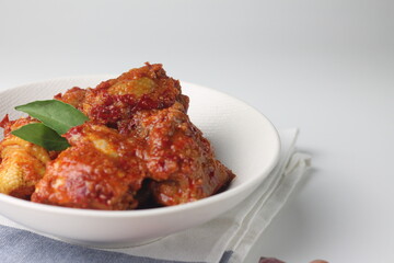Ayam Bumbu Bali or Ayam bumbu Balado or Ayam Masak merah, Indonesian traditional chicken spicy, served on ceramic plate. Usually eat with yellow rice or nasi lemak. Isolated background. Copy space.