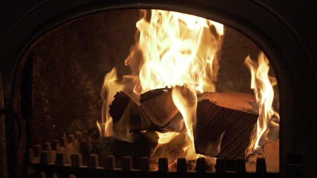 Silver Birch logs burning in wrought iron stove. MEDIUM SHOT