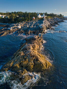 Aerial drone image of the rocky tip of the Pemaquid Point Lighthouse on the Maine Coast