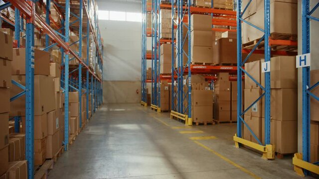 Gigantic Sunny Retail Warehouse full of Shelves with Goods in Cardboard Boxes. Logistics and Distribution Storehouse Center for further Product Delivery Packages. Descending Semi Side Camera View