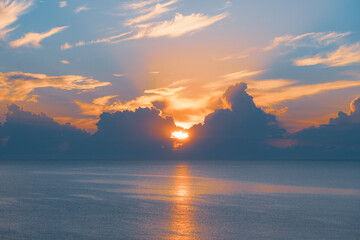 Naklejka na ściany i meble Sun rising from the sea. Colorful cloudy blue sky and sunbeams