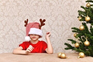 A boy in a cap, dressed in his eyes. A bewildered man sits at the Christmas tree.