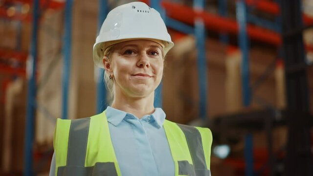 Portrait of the Beautiful Female Warehouse Inventory Manager Smiling Charmingly with Rows of Shelves Full of Merchandise, Goods and Products Packed in Cardboard Boxes Ready for Shipment. 