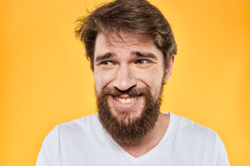 Fototapeta premium Man with emotional expression white t-shirt close-up studio yellow background