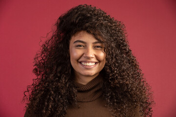 Beauty portrait of a Brazilian woman with afro hairstyle and glamour makeup. Latin woman. Mixed race. Curly hair. Hair style. Red background.