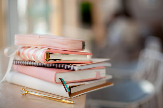 stylish designed coral and white coloured stack of diaries with gold pen.