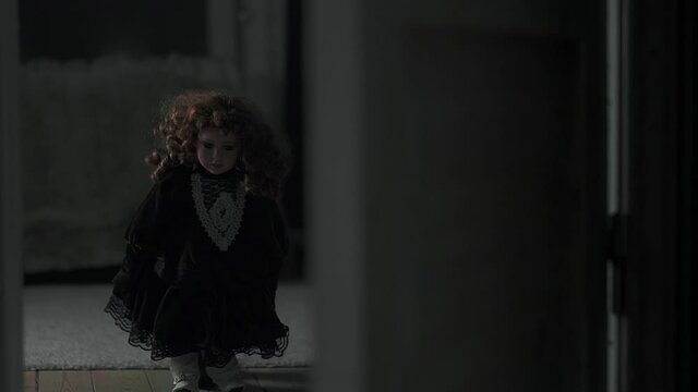 Creepy doll standing on the other side of a door. Dark setting and halloween vibe.