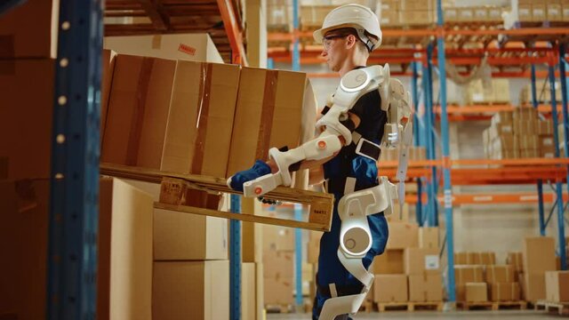 High-Tech Futuristic Warehouse: Worker Wearing Advanced Full Body Powered exoskeleton, Lifts and Walks with Heavy Pallet full of Cardboard Boxes. Delivery Exosuit amplifies strength. Slow Motion