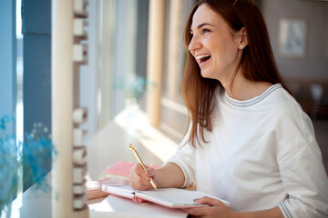 Cheerful young woman writing and keeping her personal a daily diary books.