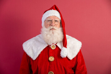 Serious Santa Claus with a red background, wearing glasses, gloves and a hat looking forward