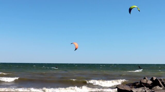 Kiteboarders on a beautiful, virtually cloudless day traversing the shoreline.