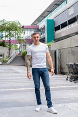 Fototapeta na wymiar Full body shot of handsome man with tattoos in the city