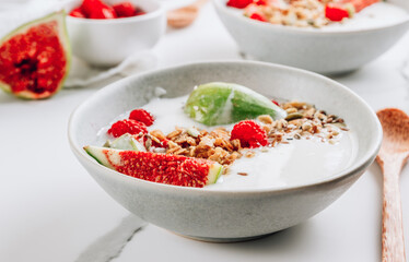 Granola with yogurt, figs and raspberries in bowls