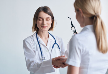 Woman doctor with glasses in hands on a light background patient communication