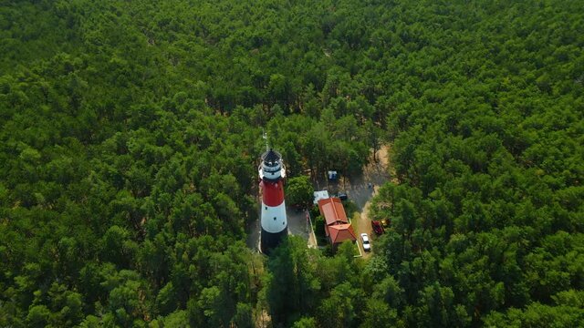 Drone spinning around Stilo Lighthouse and green forest- lighthouse located in Osetnik (formerly Stilo) on the Polish coast of the Baltic Sea, close to the village of Sasino, aerial
