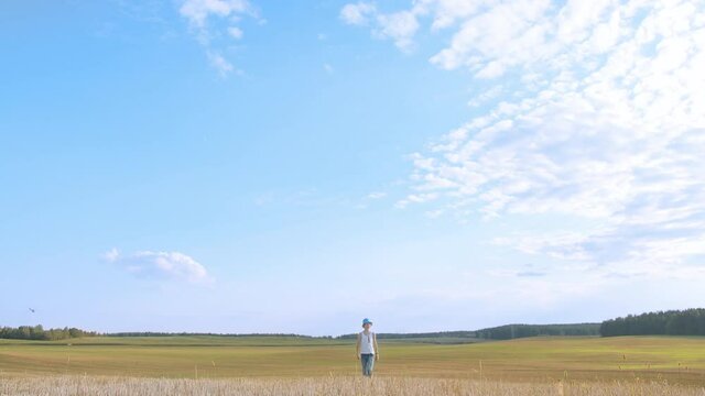 boy walks on a cut field, beautiful sky