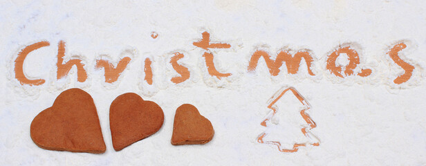 Word christmas written in flour and festive cookies or gingerbreads. Baking and festive time concept