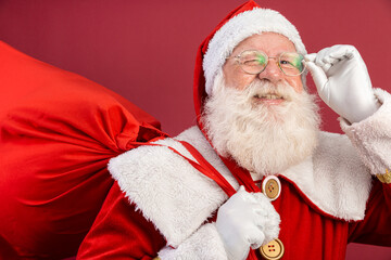 Santa Claus looking at the camera. Christmas is coming. Merry Christmas. Santa is watching. Holding his glasses.