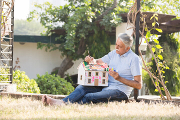 Senior man enjoy the painting in the Backyard of the House.