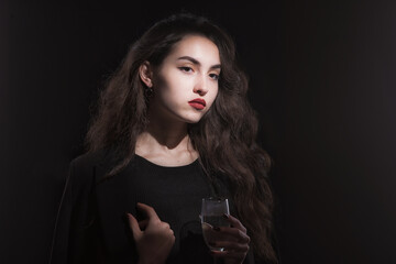 Vintage portrait with harsh light of a beautiful, slim brunette woman with bright makeup and wavy hair