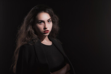 Fototapeta premium Vintage portrait with harsh light of a beautiful, slim brunette woman with bright makeup and wavy hair
