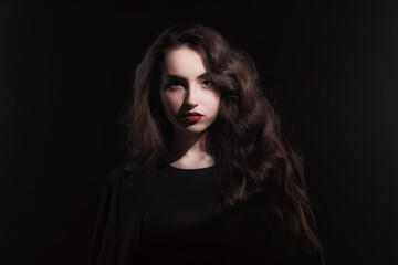 Vintage portrait with harsh light of a beautiful, slim brunette woman with bright makeup and wavy hair