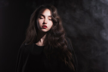 Vintage portrait with harsh light of a beautiful, slim brunette woman with bright makeup and wavy hair