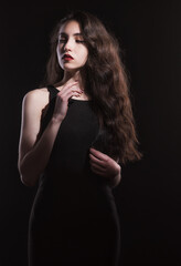 Fototapeta premium Vintage portrait with harsh light of a beautiful, slim brunette woman with bright makeup and wavy hair